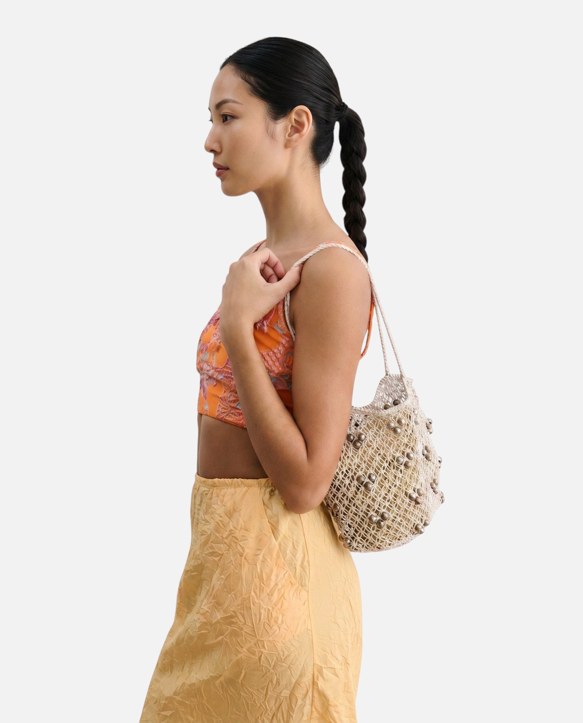 Model wearing a JONES + CO silver leather macrame mini web bag with bamboo beads over her shoulder