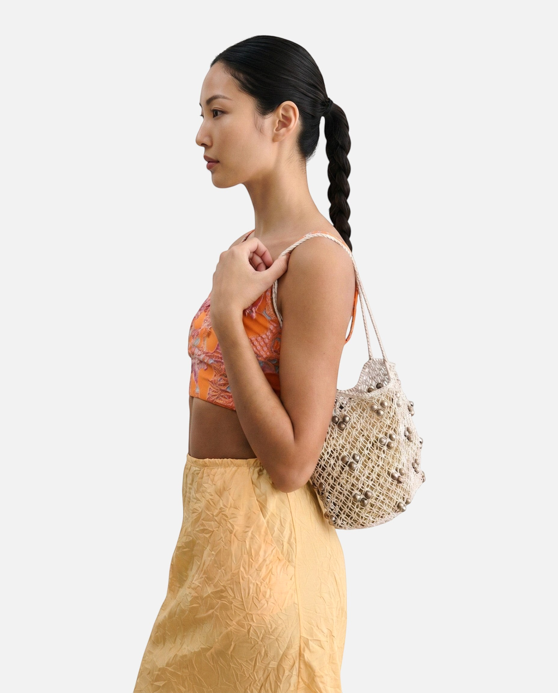 Model wearing a JONES + CO silver leather macrame mini web bag with bamboo beads over her shoulder