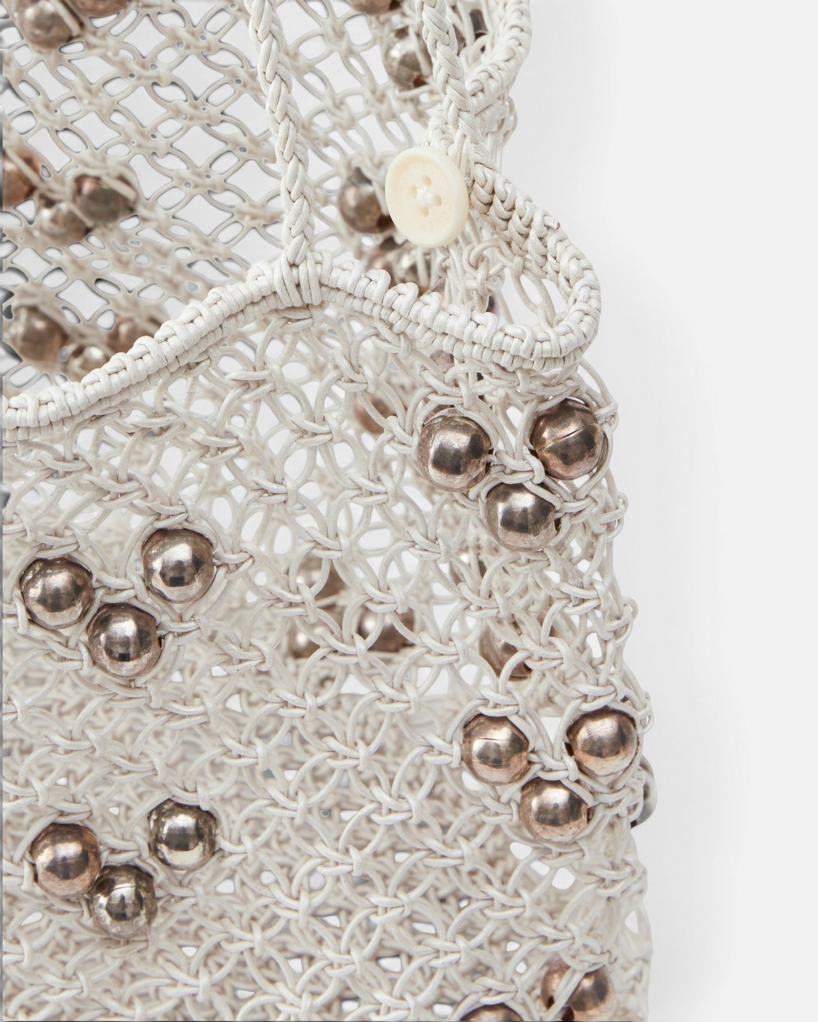JONES + CO Mini Web Bag in silver featuring intricate macrame leather weaving and metallic bamboo bead details.