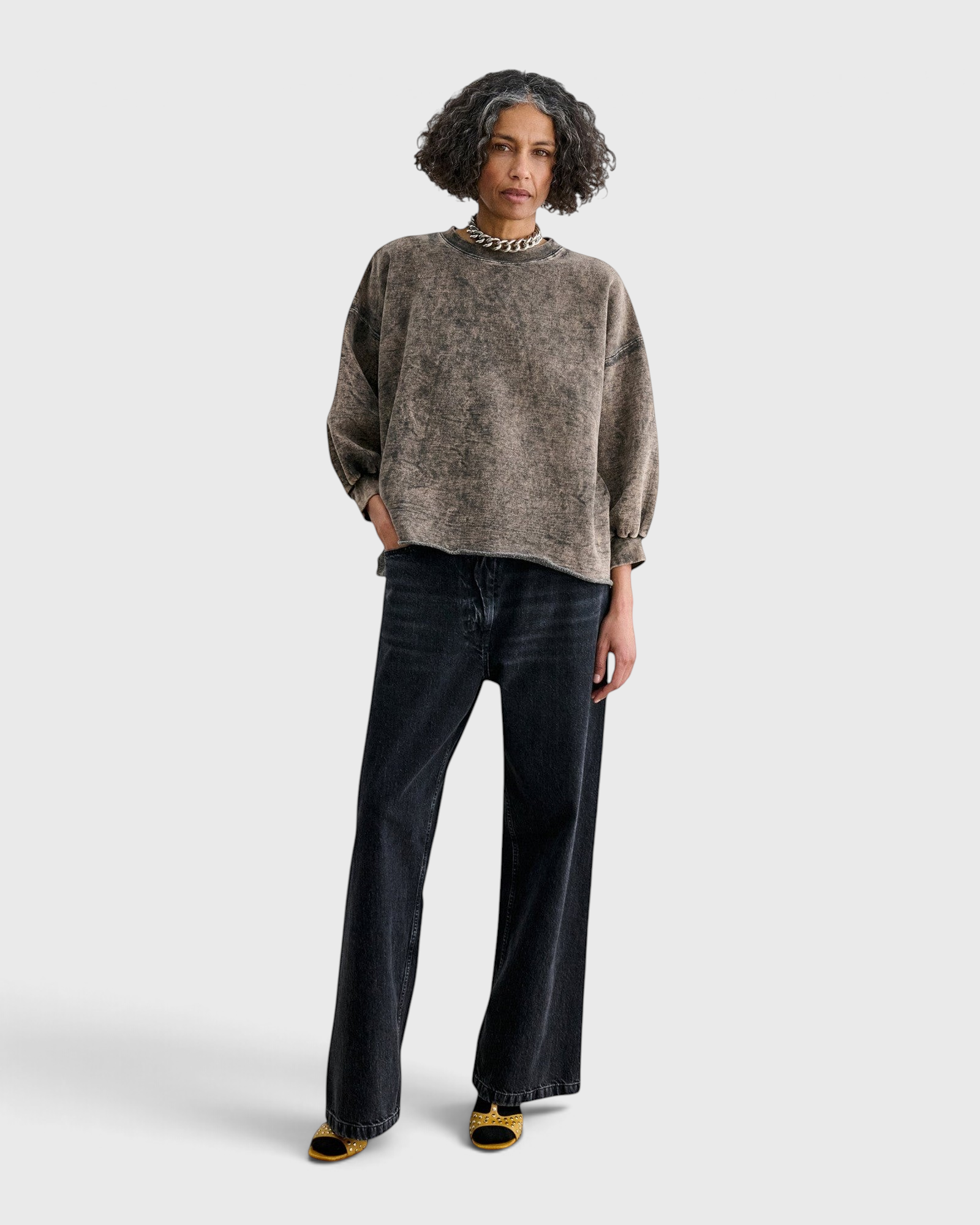 Model wearing a JONES + CO smoky hazelnut acid-overdyed cropped sweatshirt with raw-edge hem and dropped shoulders.