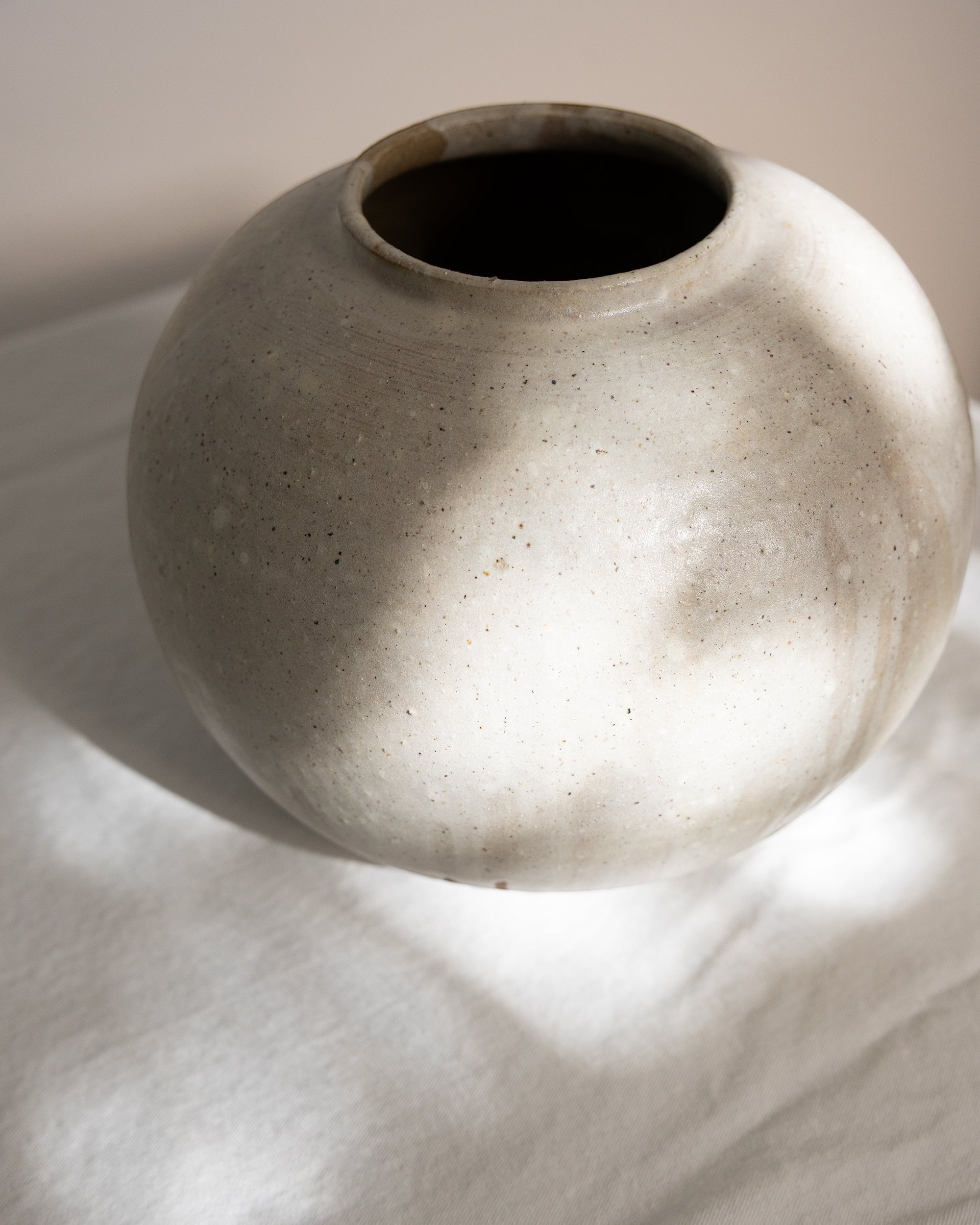 JONES + CO handthrown ceramic vase with a speckled off-white finish and rounded sculptural shape
