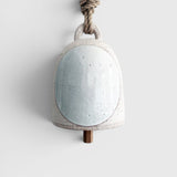 JONES + CO small round stoneware bell in white with a glazed full moon design, wood knocker, and hemp rope hanger.