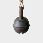 JONES + CO round extra dark stoneware jingle bell with yellow crescent detail hanging on a rustic hemp rope.