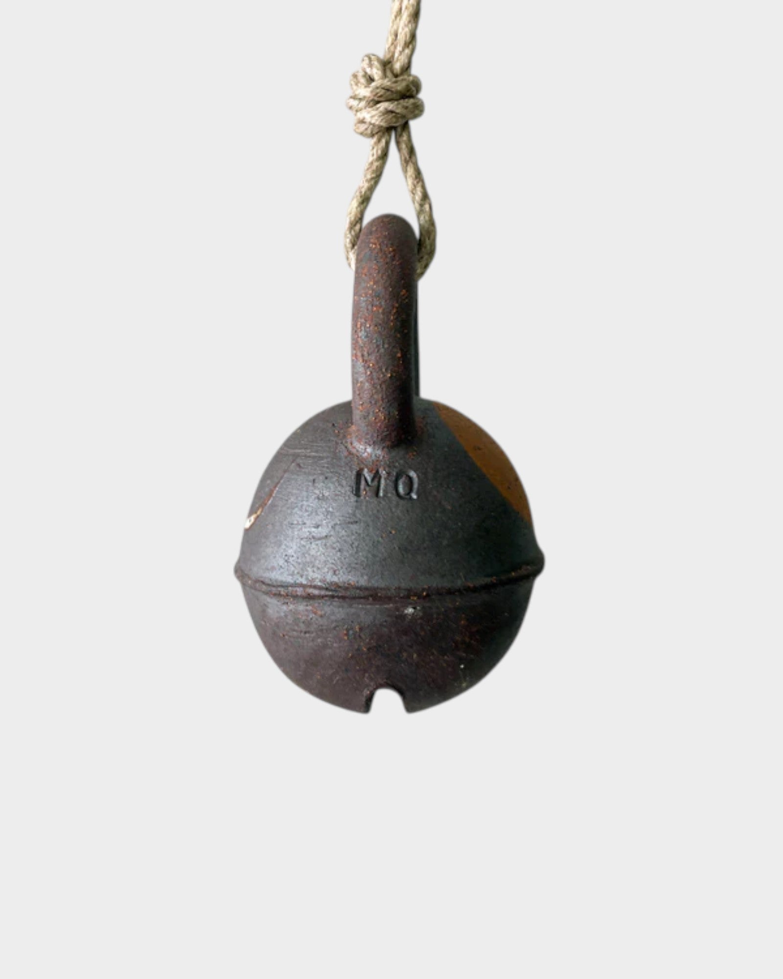 JONES + CO round extra dark stoneware jingle bell with yellow crescent detail hanging on a rustic hemp rope.