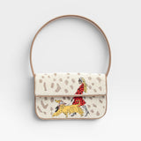 JONES + CO Tommy shoulder bag featuring hand-beaded dog walk design on cream background with vegan leather piping.