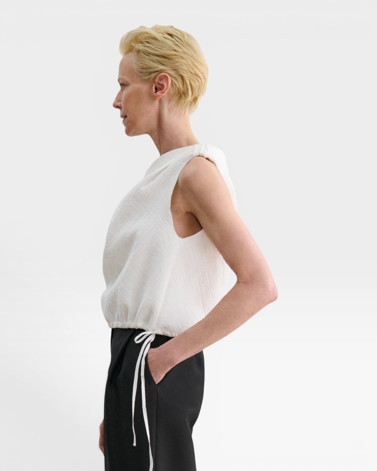 JONES + CO white one-shoulder Farfalla top in Italian Foam fabric with a draped silhouette and drawstring waist.