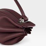 JONES + CO Bon-Bon wine-colored calf leather handbag featuring a pleated design and polished palladium brass clasp.