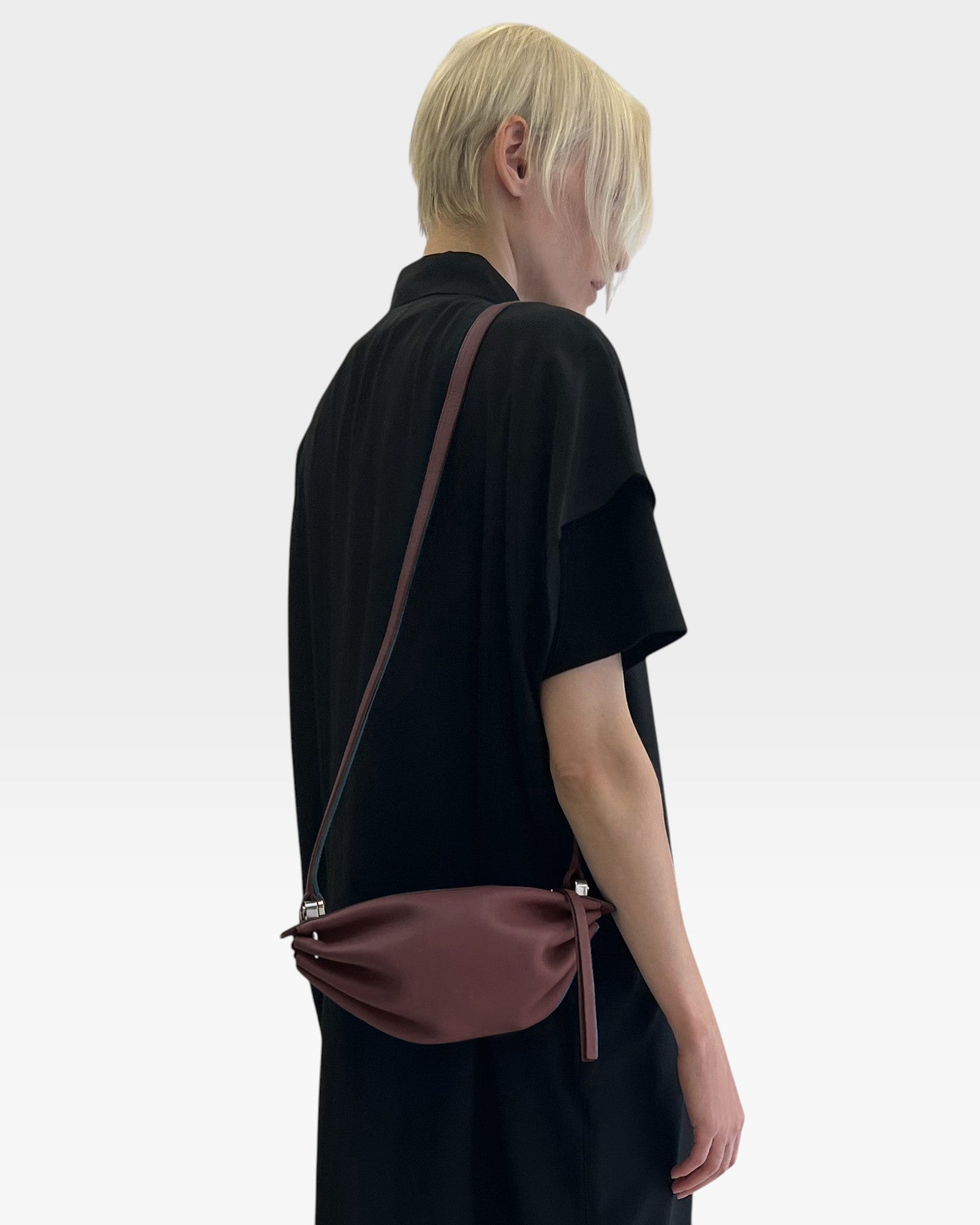 JONES + CO Bon-Bon wine-colored calf leather shoulder bag with pleated ends and palladium hardware worn by a model.