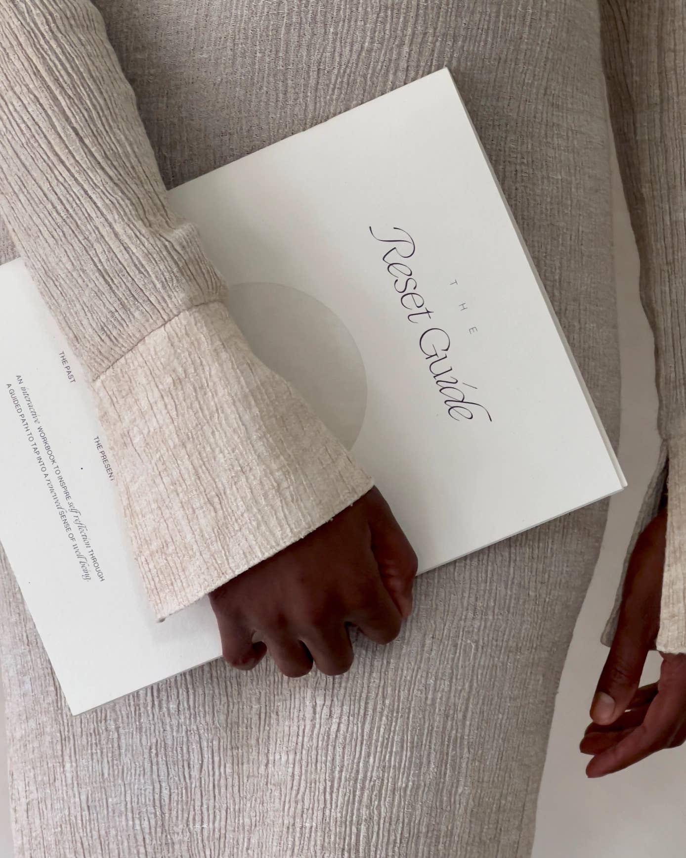 Person holding a book titled 'Reset Guide' with a neutral background