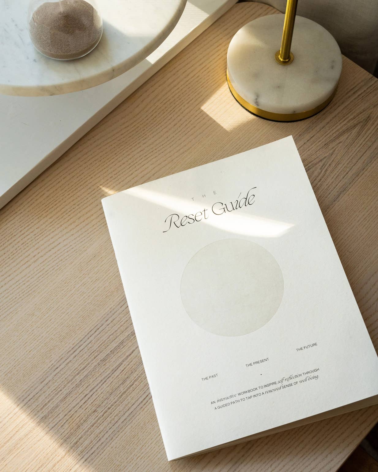 White book titled 'Reset Guide' on a wooden surface with soft shadows