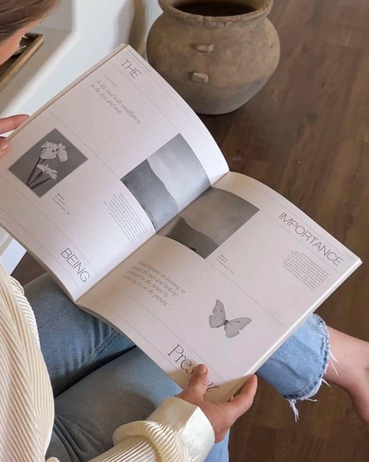 Person reading an open book with butterfly illustrations on a wooden floor.