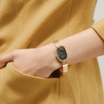 Gold watch on a wrist with a mustard yellow garment