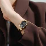 Person wearing a gold watch on a plain background