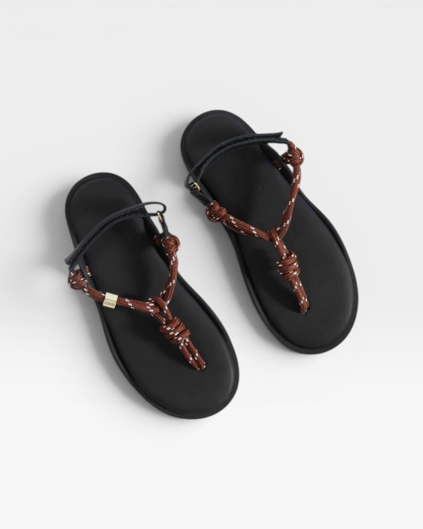 Black sandals with brown braided straps on a white background