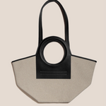 Black and beige handbag with circular handle on a beige background