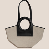 Black and beige handbag with circular handle on a beige background