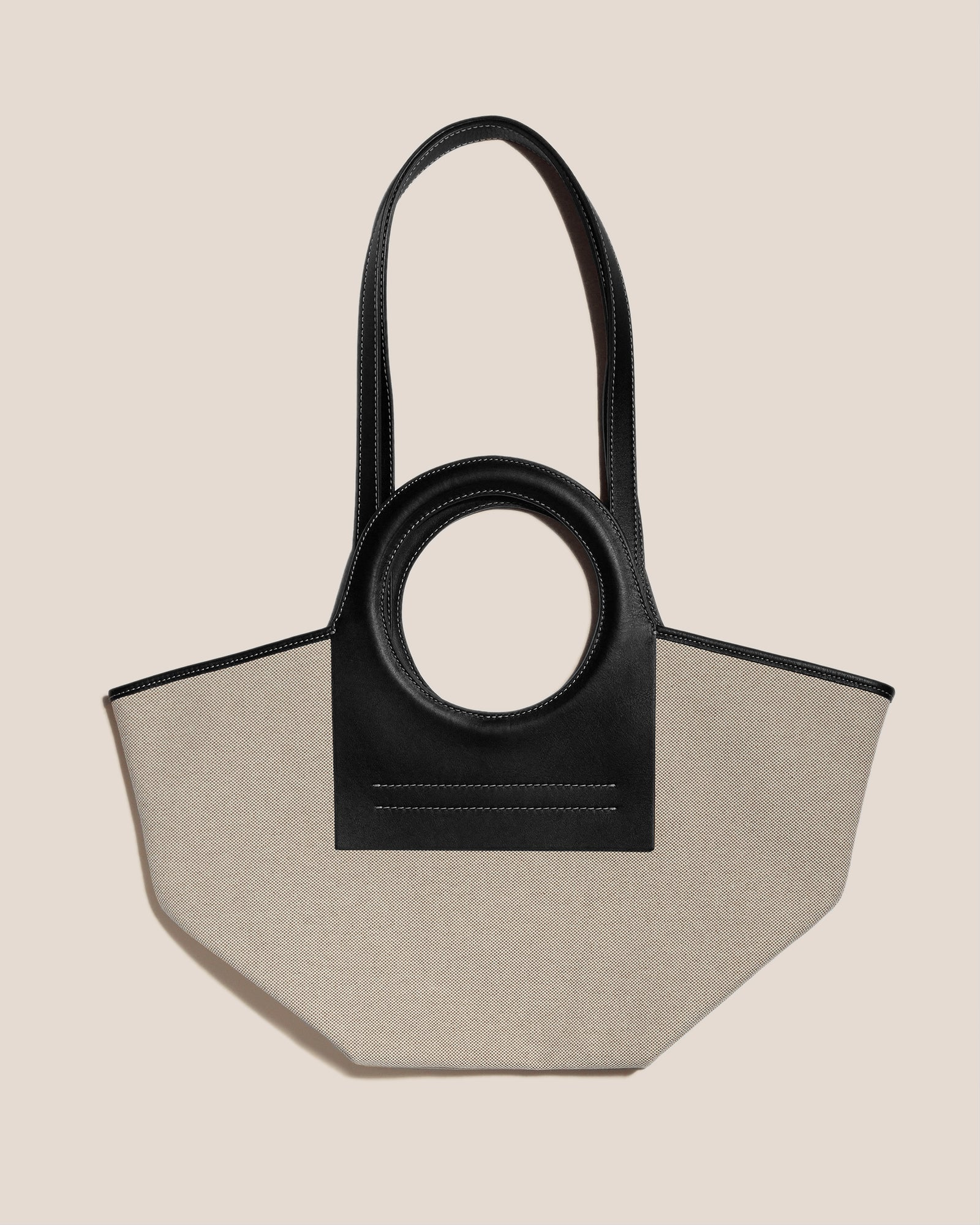 Black and beige handbag with circular handle on a beige background