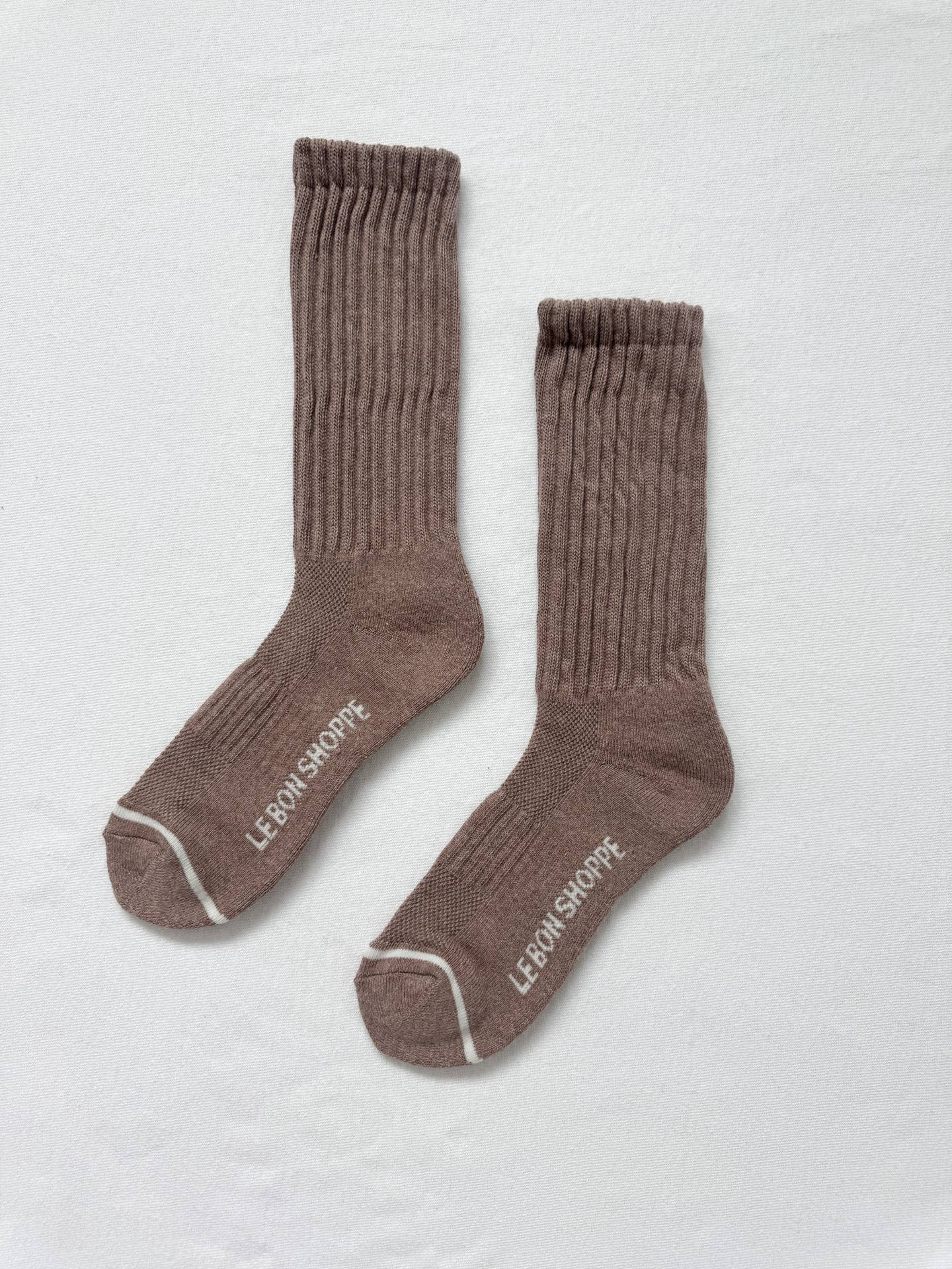 Pair of brown socks with white trim on a light gray background
