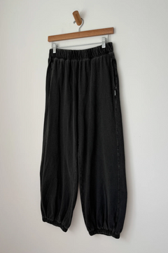 Black pants hanging on a wooden hanger against a white background
