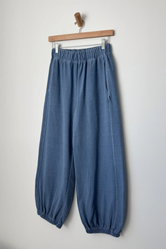 Blue pants hanging on a wooden hanger against a white background