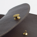 Close-up of a brown leather bag with gold hardware on a white background