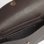 Brown leather handbag with gold hardware on a light gray background