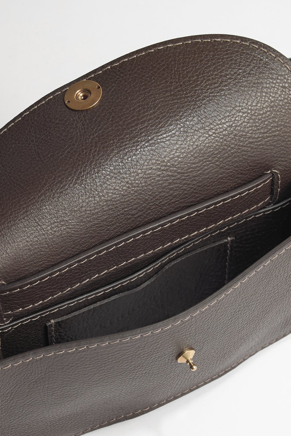 Brown leather handbag with gold hardware on a light gray background