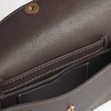 Brown leather handbag with gold hardware on a light gray background