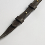 Brown leather strap with gold hardware on a light gray background