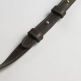 Brown leather strap with gold hardware on a light gray background