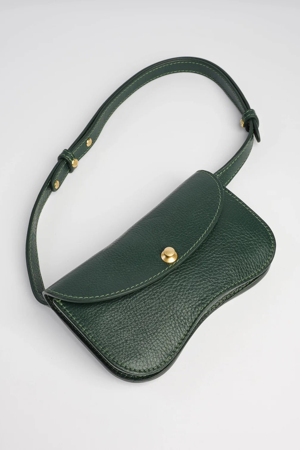 Green leather bag with a gold clasp on a light gray background