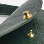 Close-up of a green leather product with gold studs on a white background