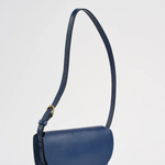 Blue handbag with a strap on a light gray background