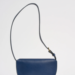 Blue leather bag with a strap on a light gray background