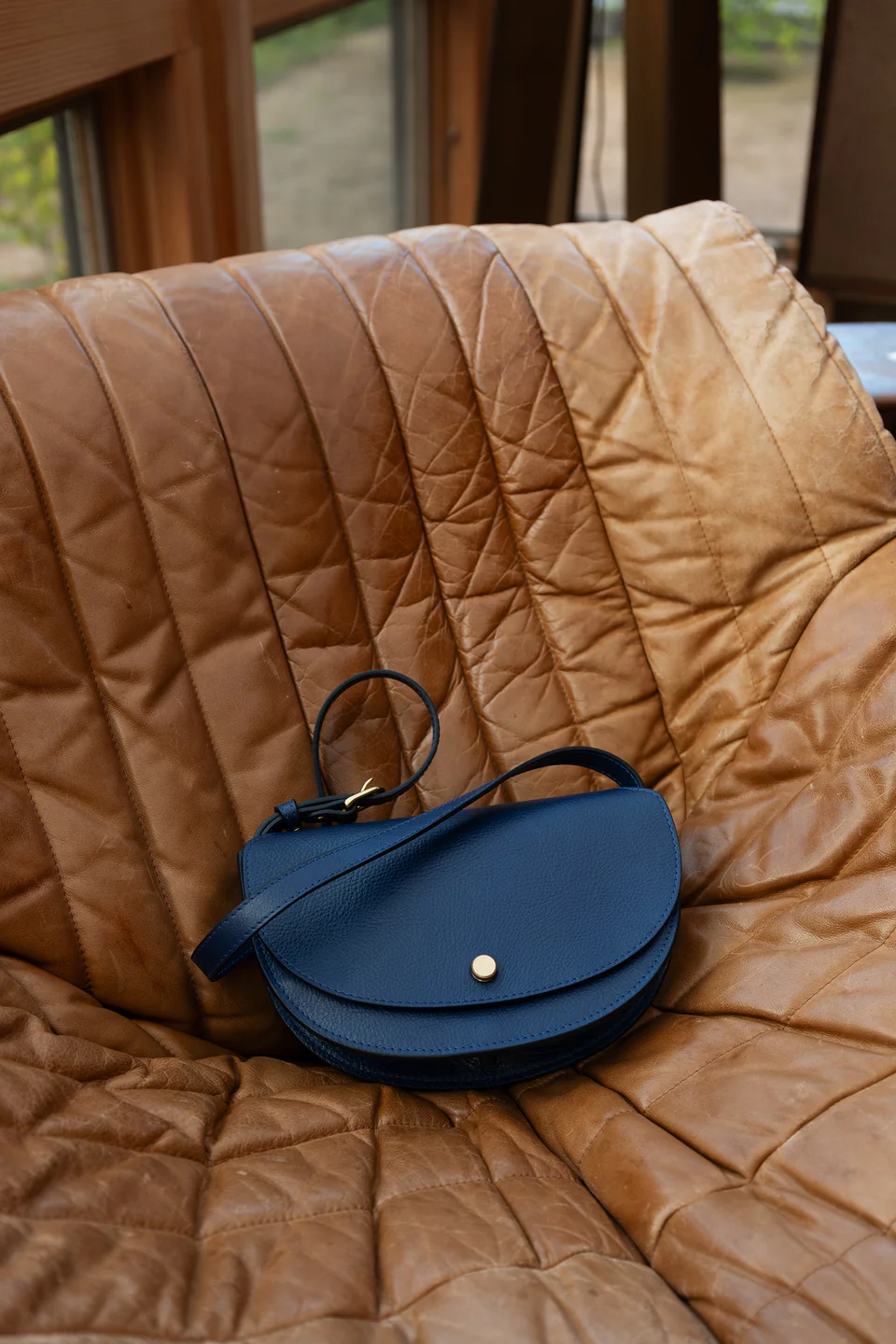 Blue leather handbag on a brown quilted surface