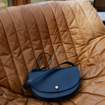 Blue leather handbag on a brown quilted surface