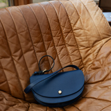Blue leather handbag on a brown quilted surface