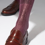 Purple socks worn with brown loafers on a light background