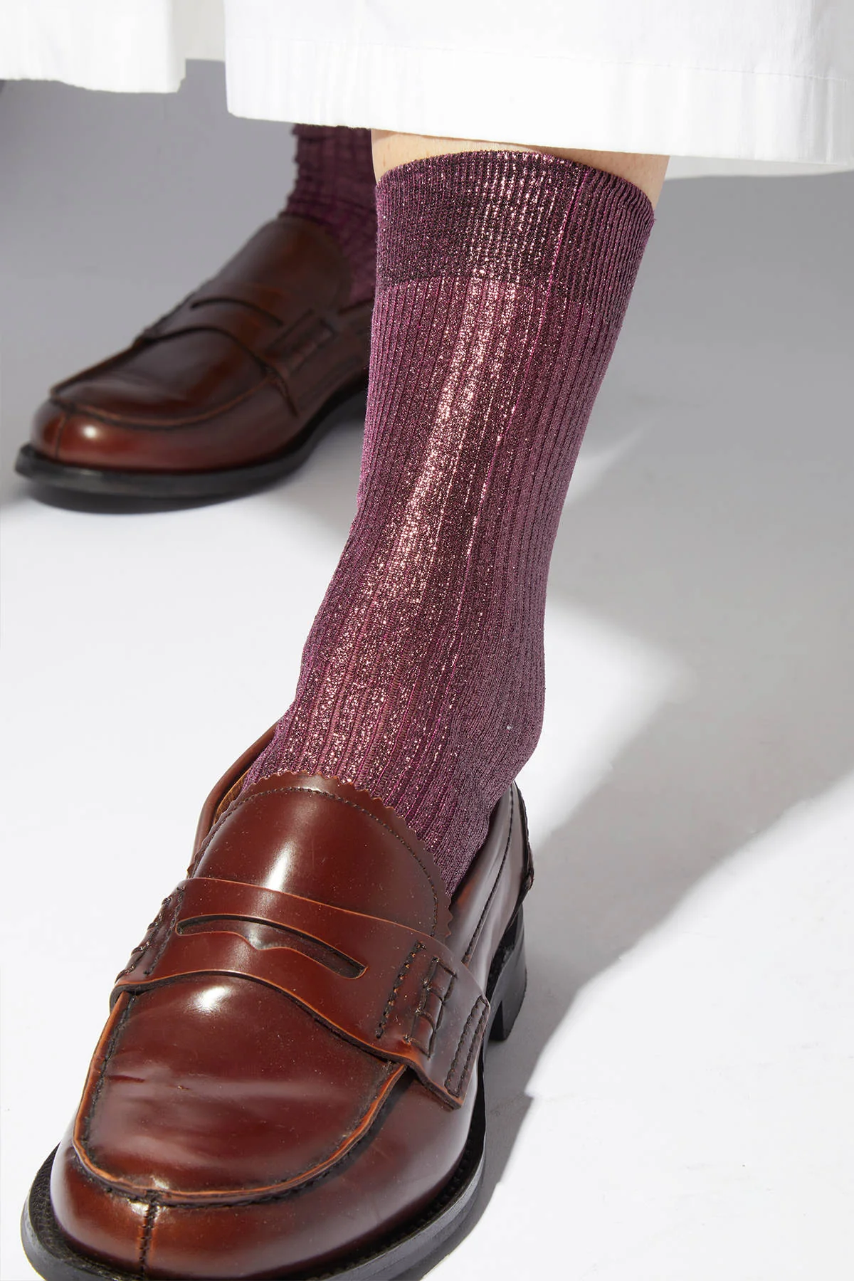 Purple socks worn with brown loafers on a light background