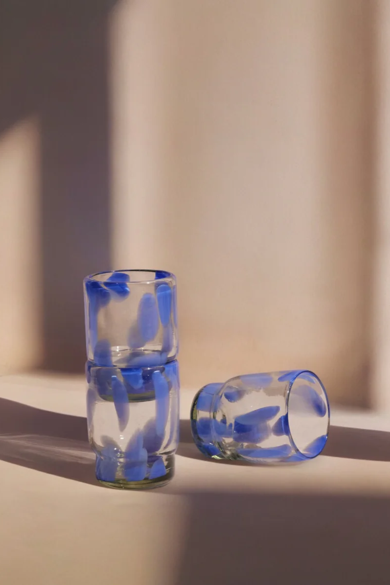 Two glass shot glasses with blue interior patterns on a light surface.