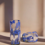 Two glass shot glasses with blue interior patterns on a light surface.
