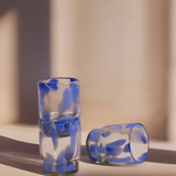 Two glass shot glasses with blue interior patterns on a light surface.