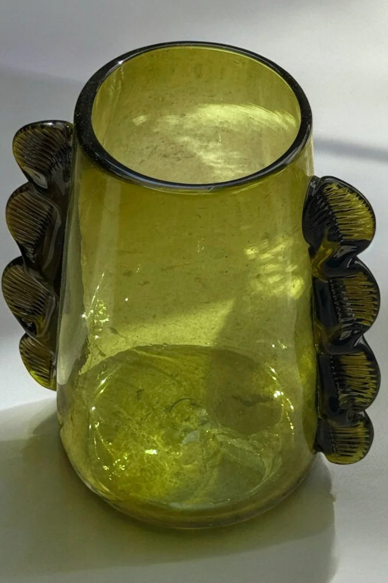 Green glass vase with decorative handles on a white background