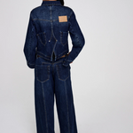 Person wearing a dark blue denim jumpsuit on a white background