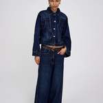 Person wearing a dark blue denim jacket and wide-leg jeans on a white background