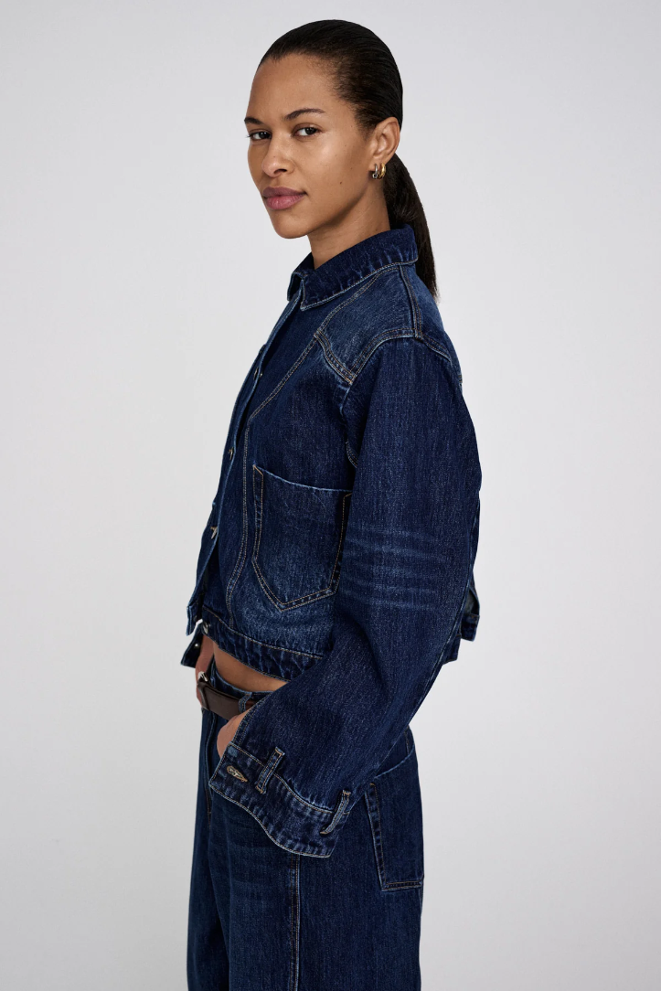 Woman wearing a long denim jacket on a white background