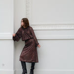Woman in a brown sequin outfit standing against a white wall