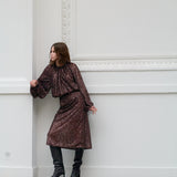Woman in a brown sequin outfit standing against a white wall