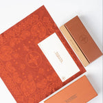 Orange patterned cleaning cloth with a white card and another orange box on a white background