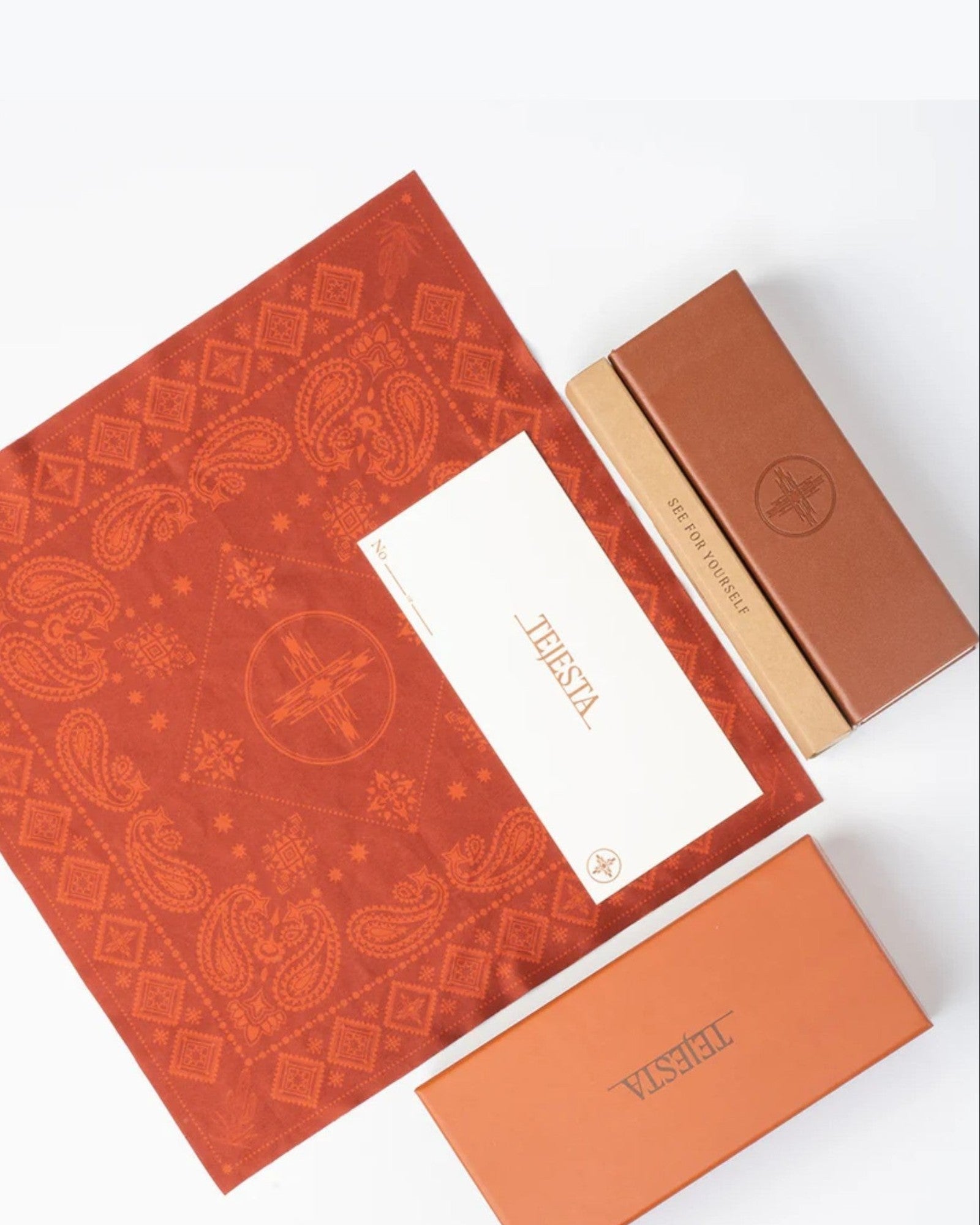 Orange patterned cleaning cloth with a white card and another orange box on a white background